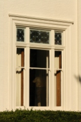 Stained glass windows are featured in the transom of large triple windows of the Greek Style.